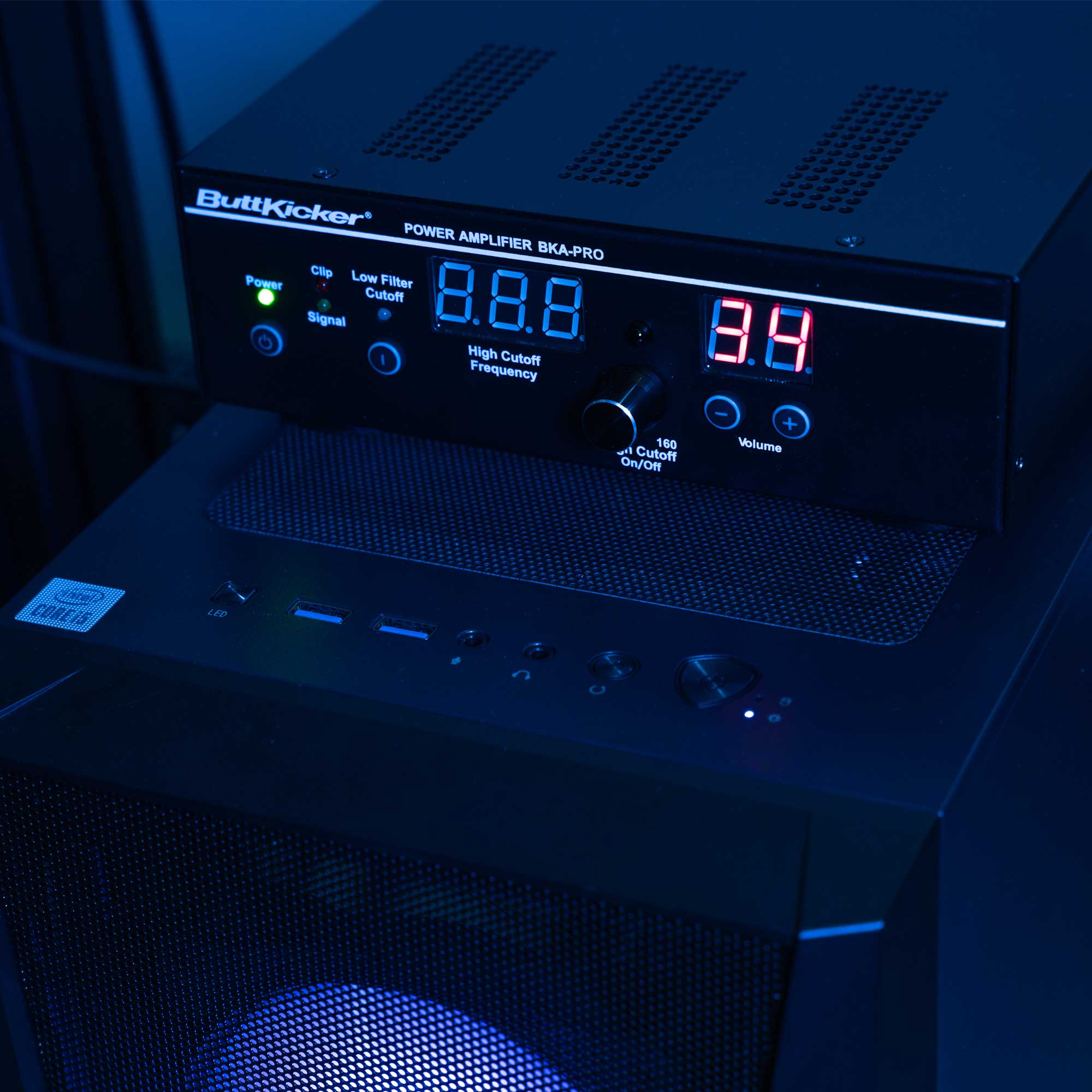 ButtKicker PRO power amplifier with digital display and wireless remote in a sim racing setup
