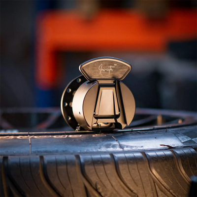 Asetek Invicta Quick Release Adapter (USB-C) displayed on a tire in a workshop setting, ideal for sim racers seeking flexibility.