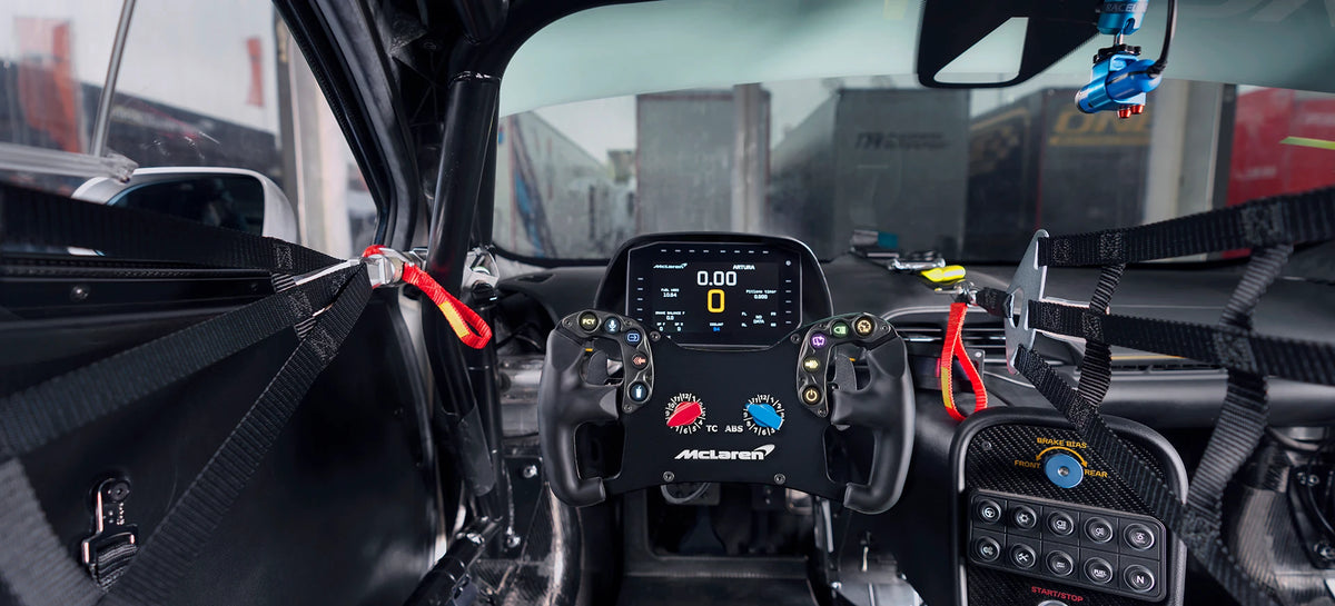 Close-up view of high-tech race car cockpit with advanced steering wheel and dashboard display in a McLaren vehicle.